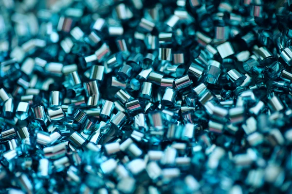 Close-up of numerous small, shiny metallic blue beads or pellets clustered together, displaying a highly reflective surface and a cylindrical shape, perfect for precision scale calibration.