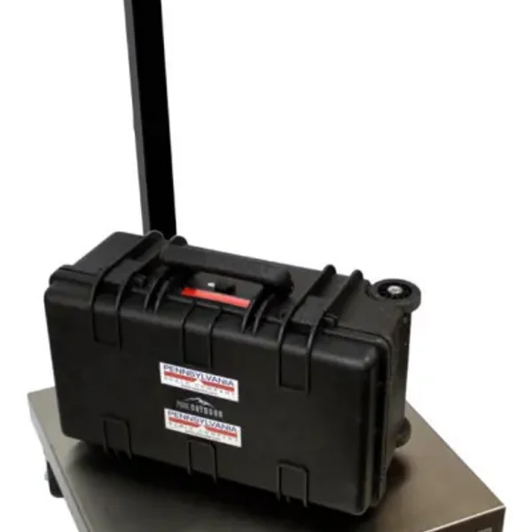 A black hard-shell case is placed on a digital scale, showcasing two stickers with red and white text on its front. Ideal for diverse weighing solutions, the digital scale features a display pole extending upward from the back left side.