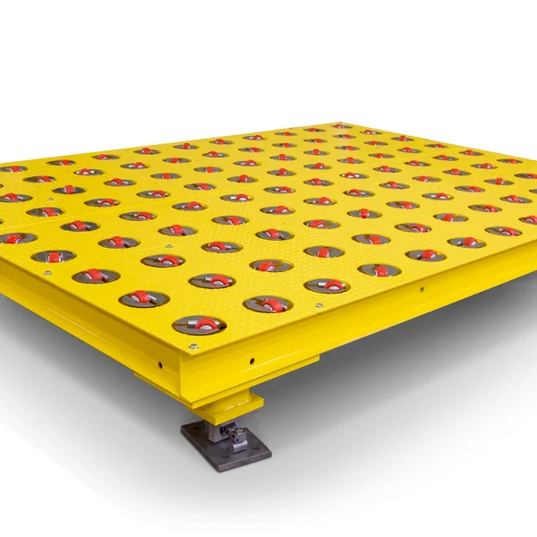 A yellow industrial conveyor platform with a grid of circular openings, each containing a red roller. The platform is elevated on a metal base with a bolt for securing or adjusting its height. This sturdy design, ideal for material handling, can integrate seamlessly into scale calibration systems.